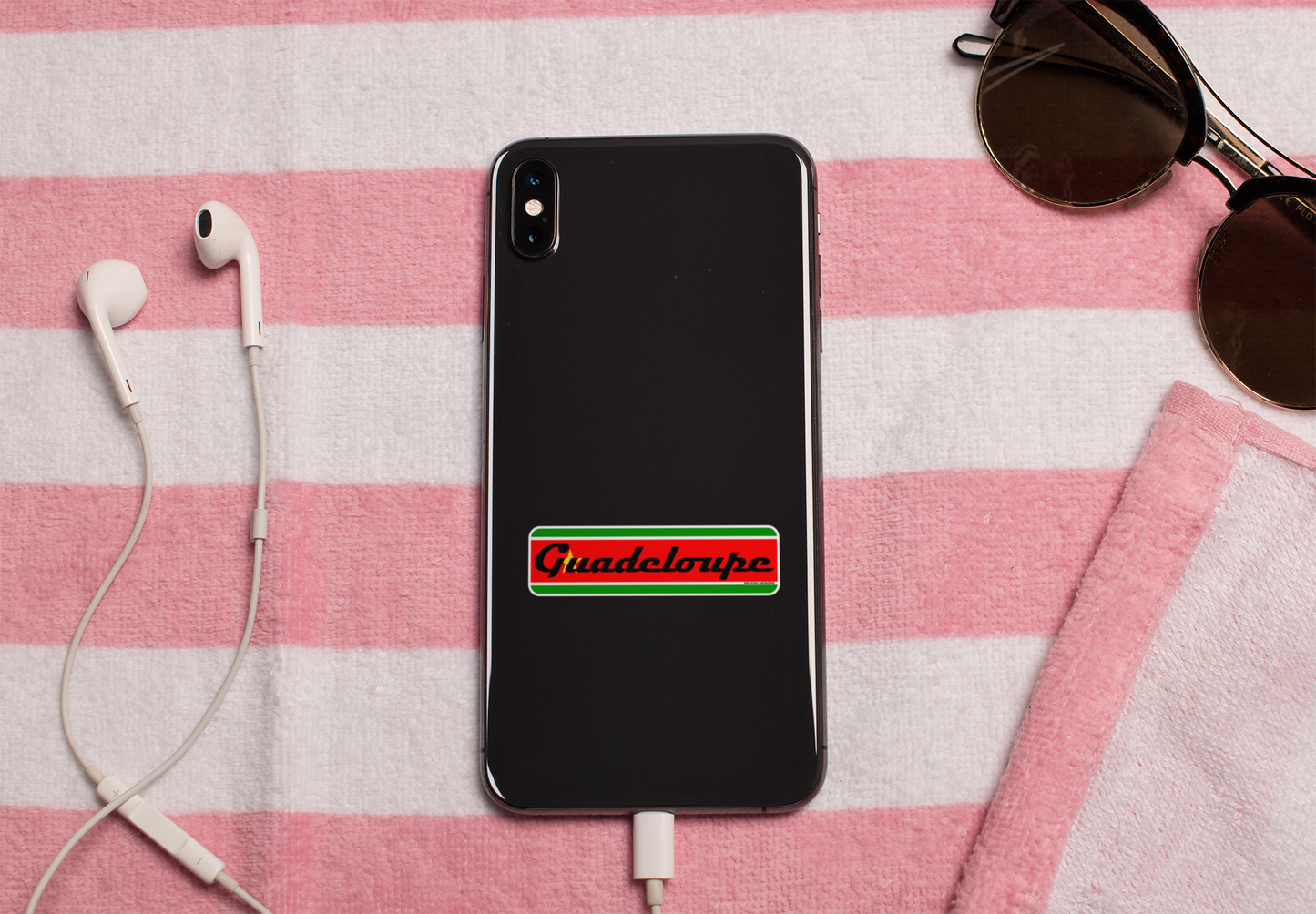 Autocollant en papier "Guadeloupe" avec drapeau régional, posé sur une serviette de plage, conçu par Prodigi.
