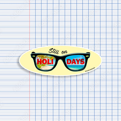 Autocollant pour lunettes "Still on Holidays" en bleu, produit par Prodigi, affiché sur une paire de lunettes noires.
