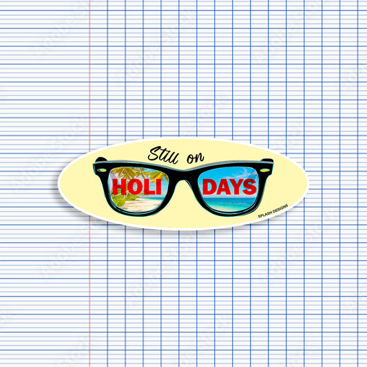 Autocollant pour lunettes "Still on Holidays" en bleu, produit par Prodigi, affiché sur une paire de lunettes noires.