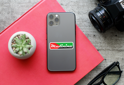 Autocollant "Madinina" en papier avec drapeau, posé à côté d’un iPhone 11 Pro, représentant le produit de la marque Prodigi.
