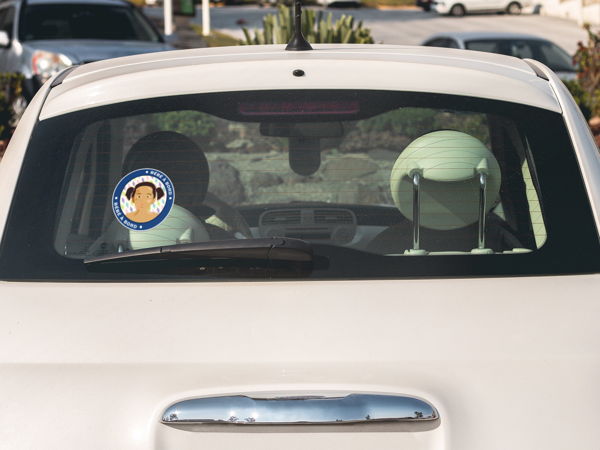 Autocollant "Bébé à bord Lou" de Prodigi sur la vitre arrière d'une voiture blanche.