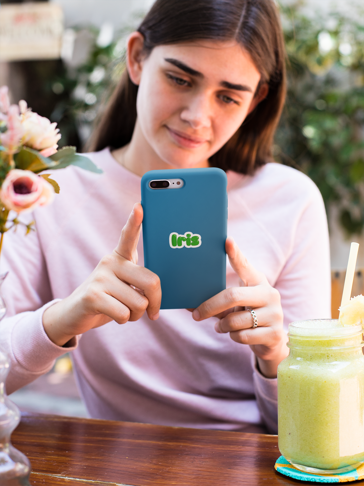 Autocollant personnalisé avec le prénom, conçu par Prodigi, illustré sur une coque d'iPhone avec une jeune femme au restaurant.