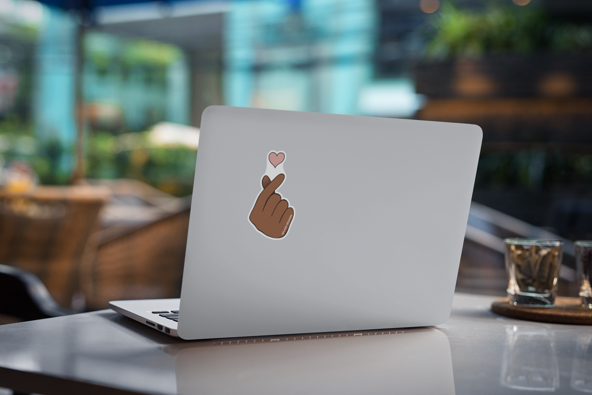 Autocollant cœur de doigt de la marque Prodigi appliqué sur une couverture d'ordinateur portable.