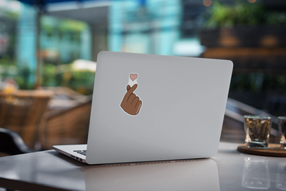 Autocollant cœur de doigt de la marque Prodigi appliqué sur une couverture d'ordinateur portable.