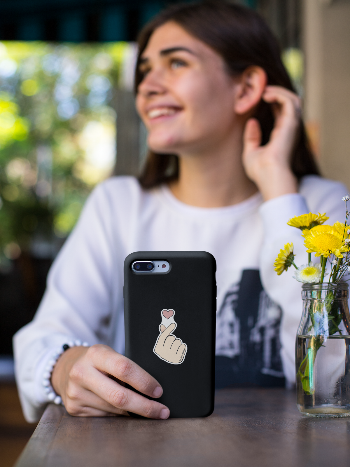 Autocollant cœur de doigt Prodigi, fille souriante tenant une coque de téléphone avec un sticker en forme de cœur sur le doigt