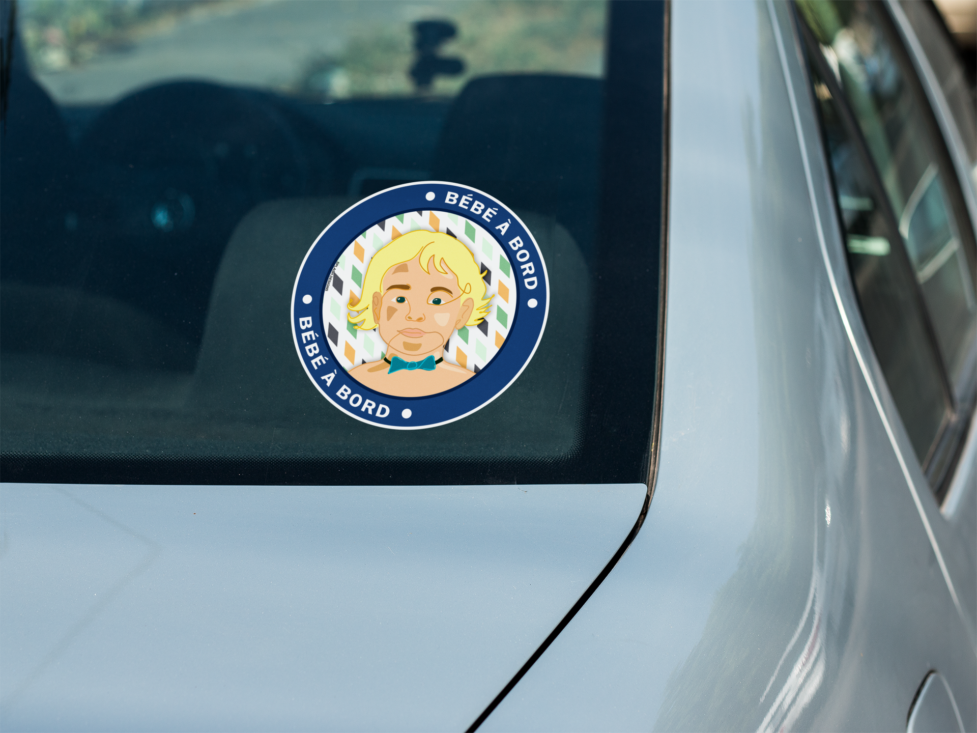 Autocollant "Bébé à bord Adrien" de Prodigi sur la vitre arrière d'une voiture, petit sticker carré pour sécurité enfant.